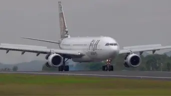 Fiji Airways airplane on the runway at Nadi International Airport with palm trees in the background